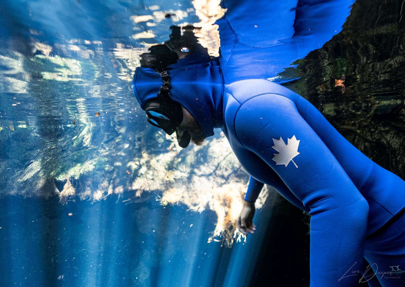 Jake underwater in a blue wetsuit with a maple leaf on the sleeve
