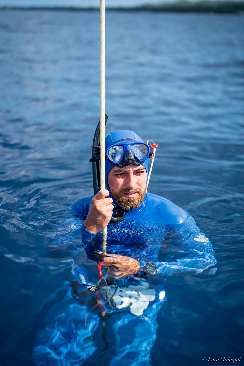 Jake holding the dive line at the surface in a blue wetsuit