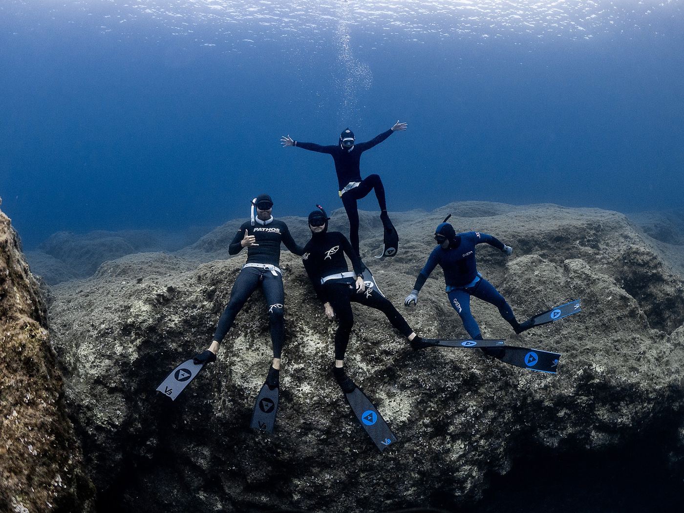 Freedivers resting on a rocky reef with their fins